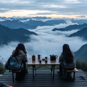 三个中国女孩在贵州拍摄云海照片,头顶放置着黑色的金属户外椅子。远处的景色被起伏的山峦和云雾缭绕所环绕。她们面前矗立着一个优雅的木质平台,上面装饰着三张精致的高区露营桌椅,有一张木桌 桌子上有一壶茶 三个杯子 营造出壮丽的自然景观。这张照片是用广角镜头拍摄的,光圈为f28,并采用电影风格的光影效果。这张相片传达出山巅和浓密的云雾的壮丽景色。