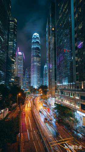 图中展现了一幅繁华都市的夜景。夜幕笼罩下,城市的高楼大厦灯火通明,玻璃幕墙反射着五彩斑斓的灯光,显得格外耀眼。画面中央是一条宽阔的城市主干道,道路上车流如织,车灯闪烁,形成了一条条光带,展现出城市夜晚的活力与繁忙。天空呈现出深蓝色,与城市的灯光交相辉映,营造出一种现代都市的独特氛围。