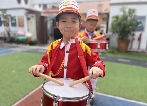 小朋友边走路边敲鼓。