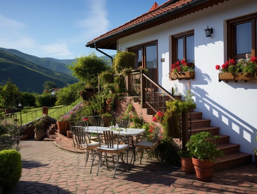 mountain village, brick-concrete structure of the country style of a small villa, front view of the house, lights, white walls, red tiles, steps, handrails, railings, wet and delicate large area of bluestone pavement, table chairs tea set, noon warm sun, close-up, garden flowers, ultra-high definition, ultra-wide angle, telephoto lens shooting